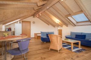 a living room with wooden ceilings and blue furniture at Ferienwohnung Schleinseeblick in Kressbronn am Bodensee