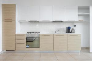 una cucina con mobili bianchi e una stufa di Villa Marconi Apartment 5 a Golfo Aranci