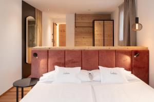 a bedroom with a white bed with a wooden headboard at Ladinia Dolomites View - Adults Only in Pozza di Fassa