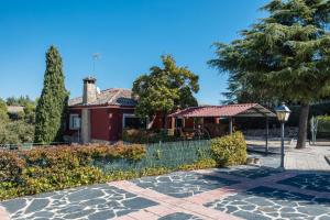 ein rotes Haus mit einem Zaun davor in der Unterkunft El Bolero De Brasal in Valdemorillo
