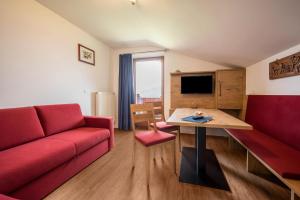 a living room with a red couch and a table at Residence Condor Apt Schlern in Maranza