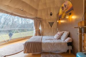 a bedroom with a bed and a large window at La Cabane aux Chevaux in Varages