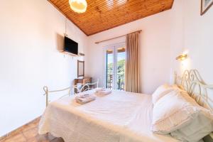 a white bedroom with a bed and a window at Korina Studios in Paleokastritsa