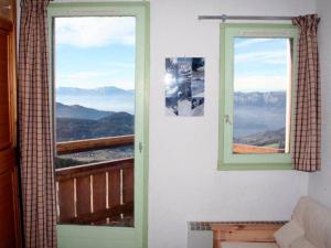 a room with two windows with a view of mountains at Appart 7 Laux - Balcon Sud in Les Adrets