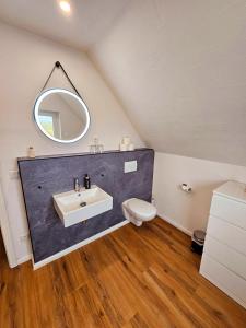 a bathroom with a sink and a toilet and a mirror at Hus Matje in Langeneß