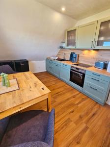 a kitchen with blue cabinets and a wooden table at Hus Matje in Langeneß