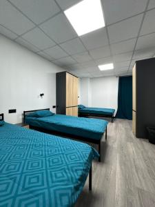 a room with three beds and blue sheets at Хостел "Батискаф" in Bila Tserkva