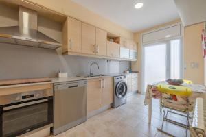 a kitchen with a sink and a table with a washing machine at Casa Marti in Cunit