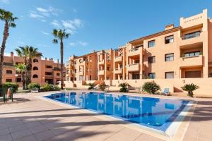 a swimming pool in front of a building with palm trees at Golf And Sun in Los Alcázares