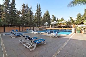 a group of lounge chairs and a swimming pool at Apartamento Balaia Praia in Albufeira