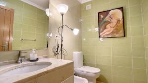 Un baño con lavabo, inodoro y espejo. en Apartamento Athena, en Monte Gordo 4 fotos más