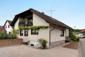 a white house with a balcony and a brick driveway at Ferienwohnung Schillinger in Sasbach am Kaiserstuhl