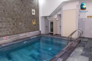 a swimming pool in a building with a brick wall at Coastal Nest - Steps to Sand in Danang