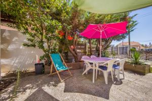 a table and chairs with a pink umbrella at Villa Mysis - Lacanau Océan in Lacanau-Océan