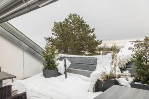 a balcony covered in snow with trees and benches at Dachatelier Überlingen in Überlingen