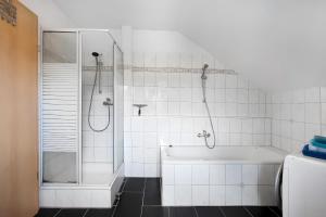 Un baño blanco con bañera y ducha. en Haus Castellbergblick 3 Whg, en Ballrechten 37 fotos más