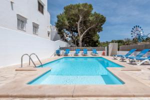 カラ・ドールにあるApartamentos Karin 1ºcの青いラウンジチェアとプール付きのスイミングプール