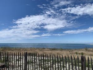 a fence on the beach with the ocean in the background at La Tomate Surfeuse 2 in Hourtin