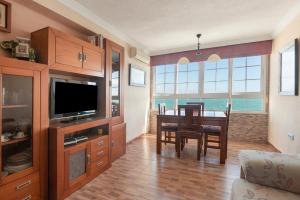 een woonkamer met een eettafel en een televisie bij Apartamento primerísima linea playa in Málaga