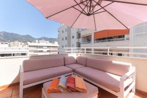 a couch on a balcony with an umbrella at Penthouse Apartment in Marbella