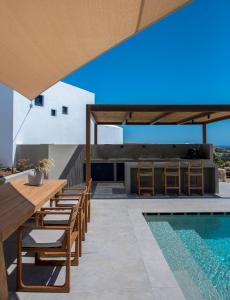 a patio with a table and chairs next to a swimming pool at ANOTERRA VILLAS -Anemone in Ambelas
