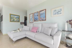 a white living room with a white couch with a pink pillow at Merlín 1-1 in Playa de San Juan