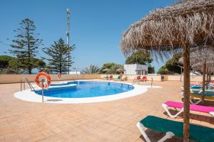 ロス・カーニョス・デ・メカにあるApartamento En Los Caños De Mecaのスイミングプール(椅子、わらパラソル付)