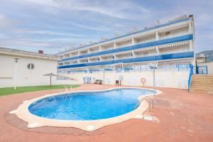 a swimming pool in front of a large building at Apartamento Merida in Alcanar