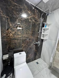 a bathroom with a toilet and a glass shower at Barn House Guba in Qǝçrǝş