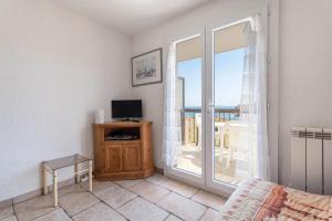 コリウールにあるAppartement terrasse vue merのリビングルーム(テレビ付)、景色を望む窓が備わります。