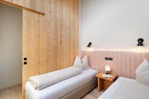 a bedroom with two beds and a wooden wall at Oberplunerhof Luxury Chalet Skyline in Colli in Pusteria
