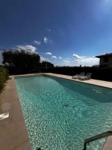 a swimming pool with blue water and two chairs at Appartamenti Villafiorito in Lazise