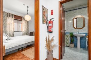 ein Schlafzimmer mit einem Bett und ein Badezimmer mit einem Waschbecken in der Unterkunft Burgau Fisherman's Cottage in Burgau