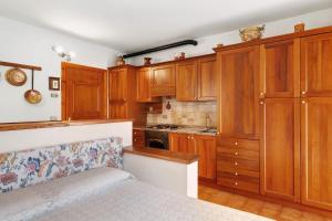 a kitchen with wooden cabinets and a bed in it at Monolocale Monti Pallidi in Domegge di Cadore