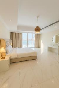 a white bedroom with a bed and a large window at درة العروس فيلا نجمة البحر in Durat Alarous +24 photos