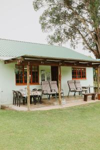 ein Haus mit Stühlen und einem Tisch davor in der Unterkunft Cicada Cottage Peaceful Drakensberg Retreat in Underberg