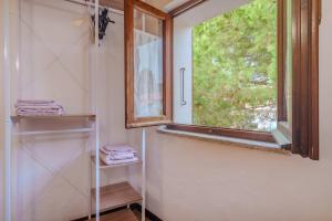 Casa TamponiBurricheddu 1的浴室设有窗户和带毛巾的架子。 更多16张照片