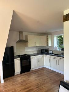 a kitchen with white cabinets and black appliances at Beechen Lodges in Bishops Waltham