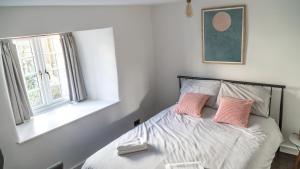 a bedroom with a bed with two pink pillows at Mor Ki -A perfectly situated modern flat in Looe in Looe