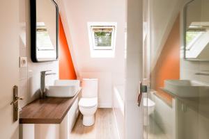an orange and white bathroom with a toilet and sink at Maison au milieu d'un parc arboré in Le Faouët +19 photos