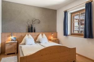een slaapkamer met een houten bed met kussens en een raam bij Woehrmannhof Apt Spinnrad in Feldthurns