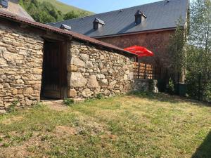 ein Steingebäude mit einer Scheune mit einem roten Regenschirm in der Unterkunft Chaleureuse Maison de Montagne in Garin