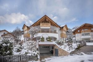 ein Haus im Schnee mit einem Zaun in der Unterkunft Ciasa Tlara App Alma in St. Vigil