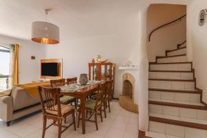 a dining room and living room with a table and a fireplace at Vila Mourisca in Armação de Pêra