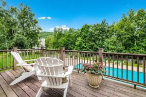 a deck with two chairs and a table and a pool at The Valley Inn, an Ascend Collection Hotel in Waterville Valley