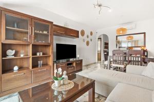 a living room with a couch and a tv at Top Floor Fuengirola Park Apartment in Fuengirola