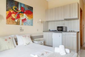 a bedroom with a white bed and a kitchen at Nontas Home 23 in Kalamitsi