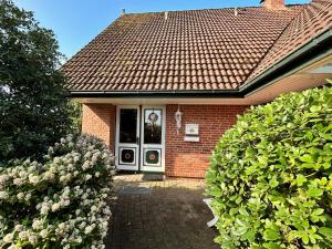 une maison en briques rouges avec une porte et deux buissons dans l'établissement Ferienwohnungen Altes Land I Jork-Borstel, à Jork