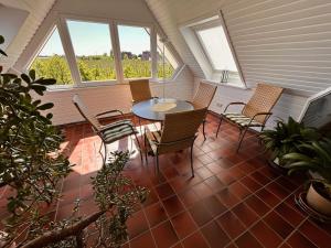 un porche avec une table, des chaises et des fenêtres dans l'établissement Ferienwohnungen Altes Land I Jork-Borstel, à Jork
