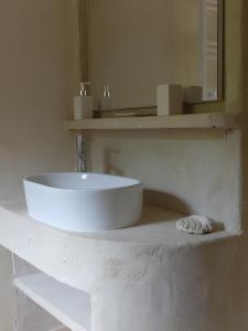 een witte badkamer met een wastafel en een spiegel bij Gîte Le Chant Des Oiseaux in Sahorre